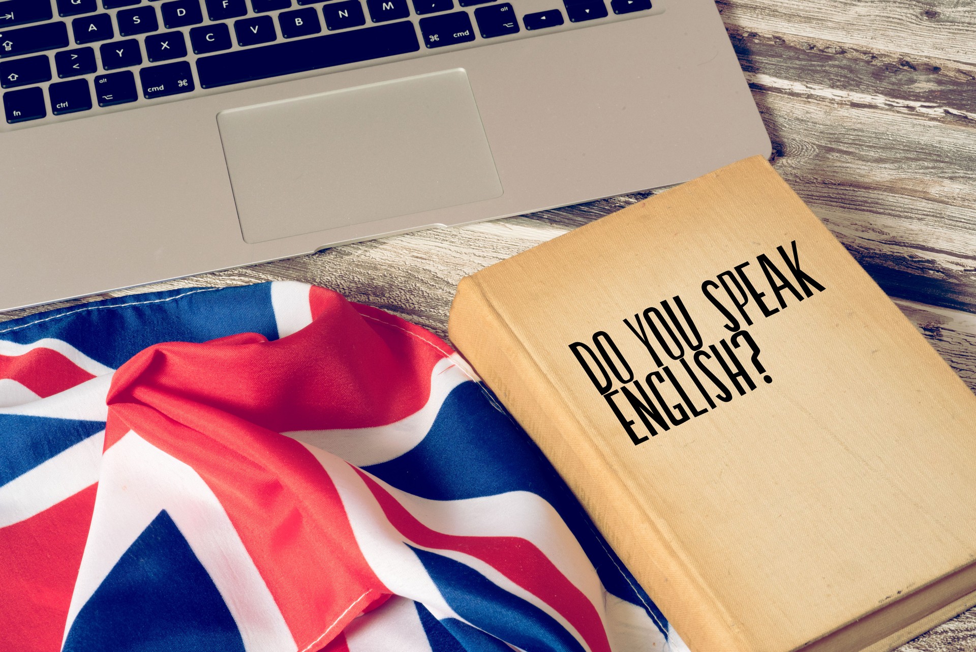 Un computer, bandiera del Regno Unito e libro intitolato Do you speak english?